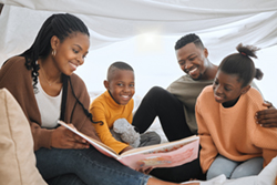Parents reading with their son and daughter in an indoor tent