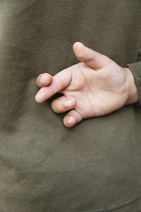 A child's hand with crossed fingers behind back.